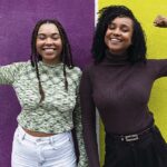 Happy friends flexing muscles in front of purple and yellow wall