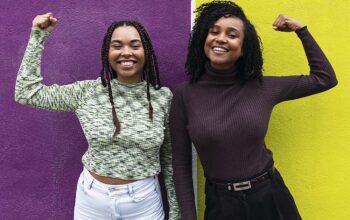 Happy friends flexing muscles in front of purple and yellow wall